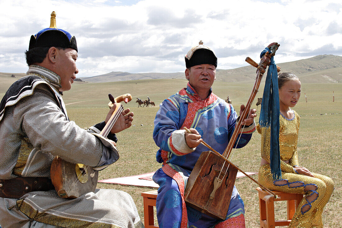 Mongol musicians, perform 'Khoomii' or throat singing a 'Urtyn Duu' or long epic song, and play 'Morin Khuur'  a horse headed string instrument which are unique and most popular in Mongolia.  Annual Naadam festival, Kharakhorin, Central Monglia.