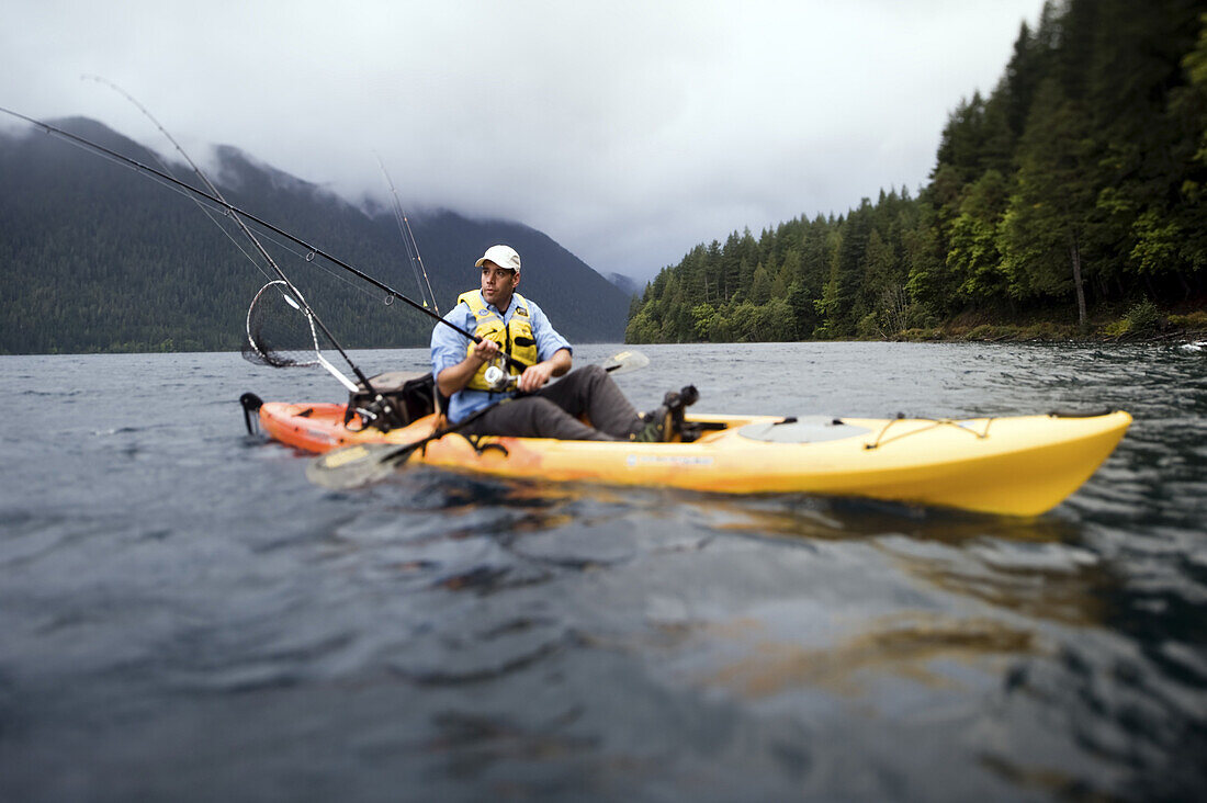 Todd Van Raden kayak fishing in a yellow and orange kayak on Lake Crescent, Olympic National Park, Washington, USA on October 7th 2008. He is kayaking in a Wilderness Systems Tarpon fishing kayak.