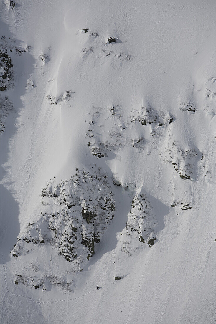 A lone mountaineer crosses underneath some of the gullies on Tuckerman Ravine on the shoulder of Mt. Washington, the highest peak in New England,  and the White Mountains of New Hampshire.