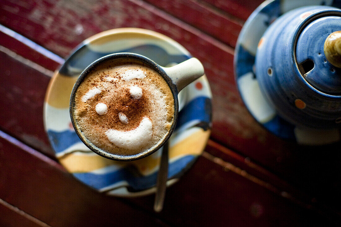 Close up photo of a cup of espresso with a smiling face made of foam.