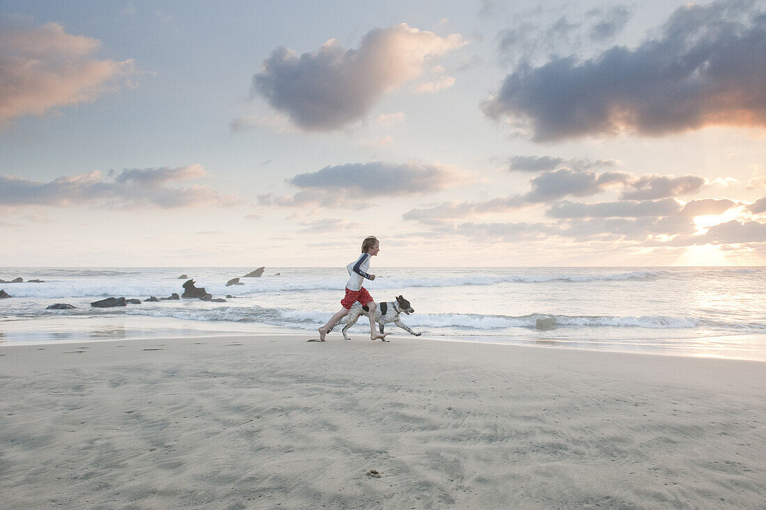 Aidan Steele, age 12, and a dog named Mancha Spot, run along a quiet beach at sunset in Troncones, Mexico on March 29, 2009.