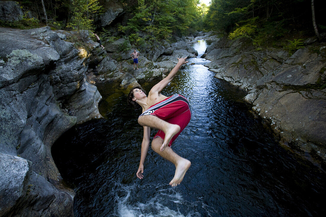 A group of teenagers jump off of a cliff at a secret swimming hole near Bethel, Maine.