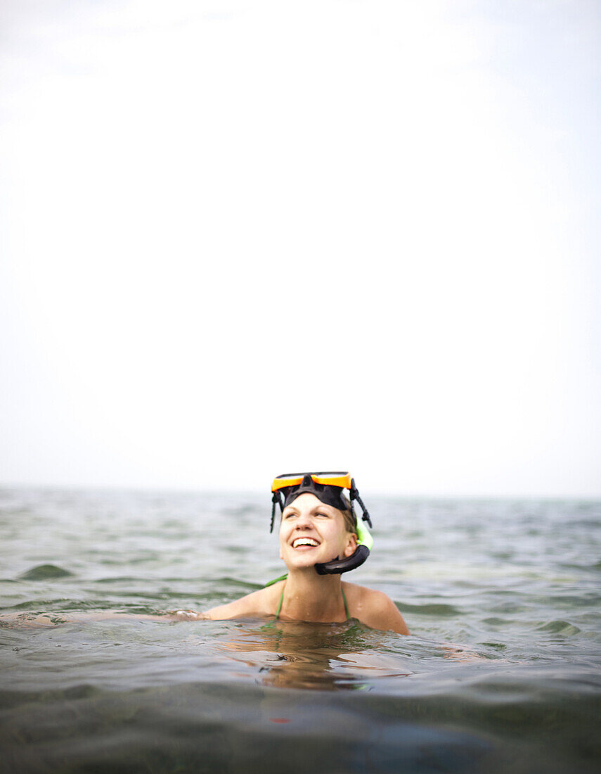 Ambergris Cay, Belize. A woman smiles with a snorkel and mask on her head.