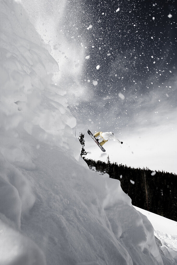 Side angle view of a snowboarder spinning off a jump in the Colorado backcountry.