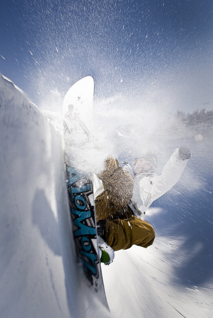 Colin Spencer spraying snow in a surf style layback on 1/4 pipe wall.