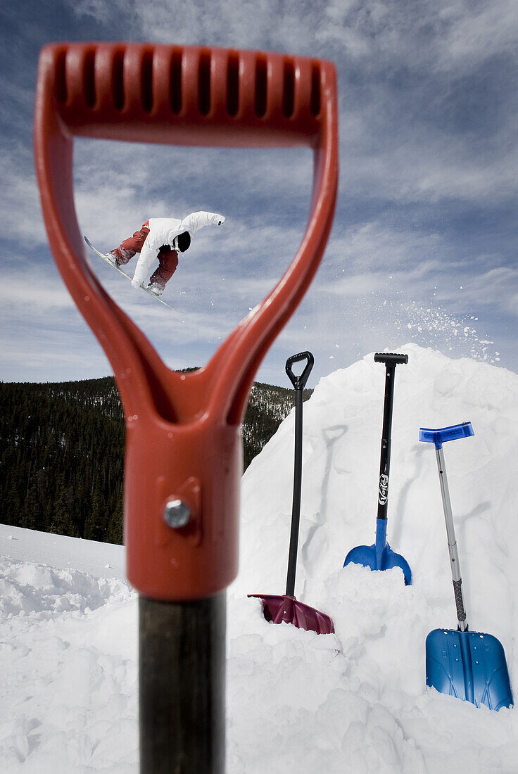 Professional snowboarder Colin Spencer spinning off a jump while being framed through a the shovel handle in Breckenridge, Colorado 2009.