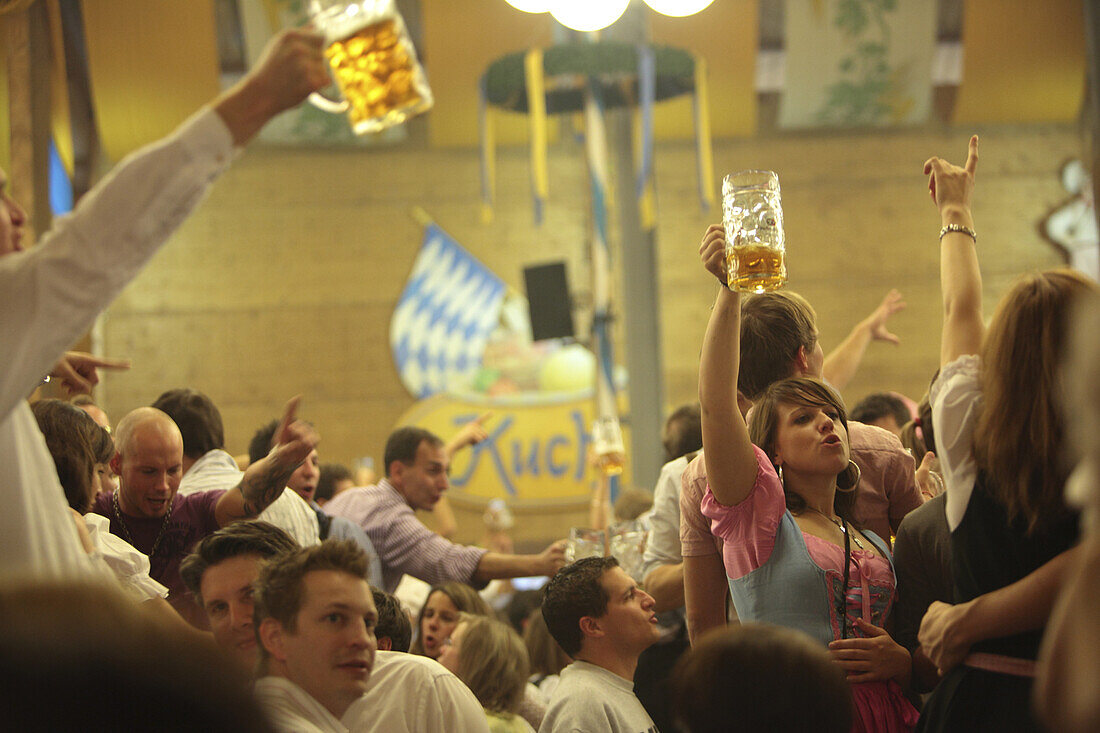Revelers raise their beer steins to toast at Oktoberfest, Munich, Bavaria, Germany.