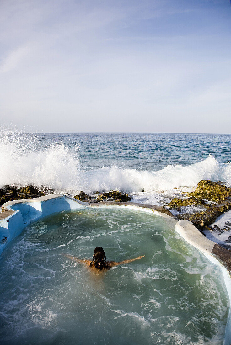 JAMAICA. A woman enjoys a small oceanside pool at a local, organic spa resort.