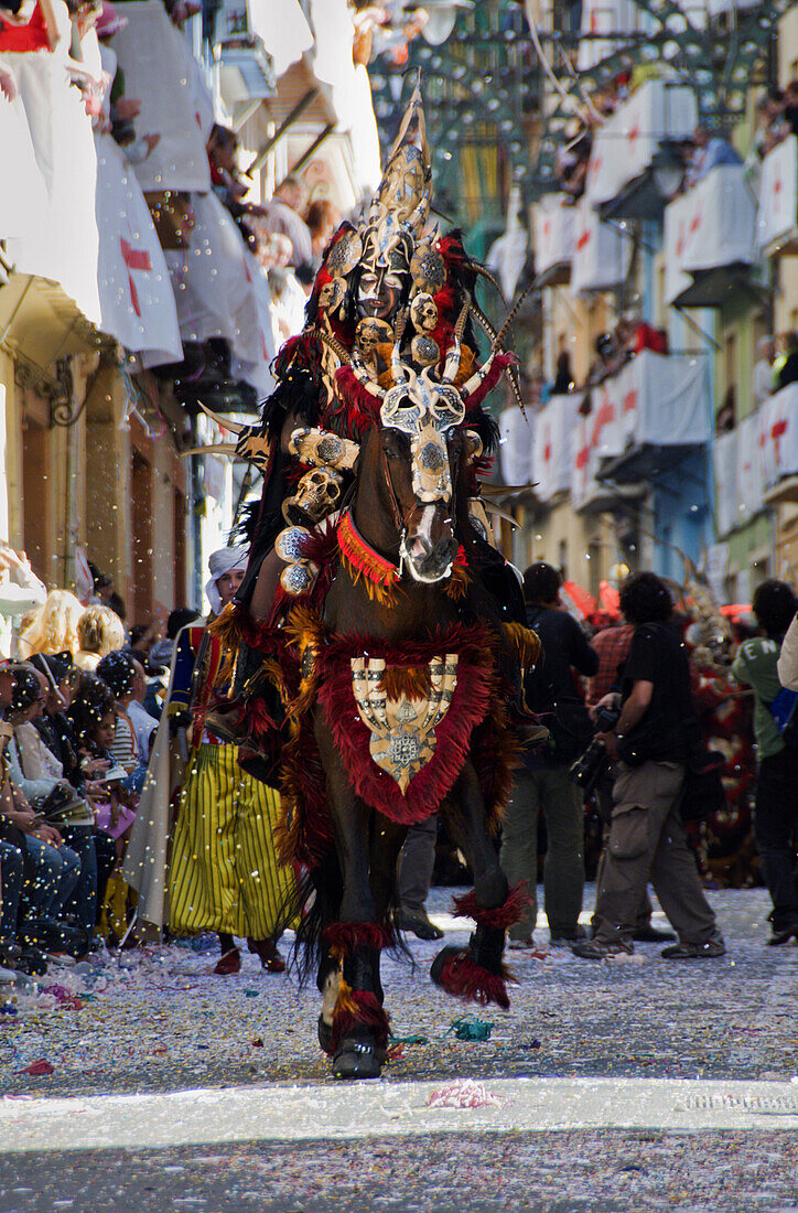 A man, dressed in an elaborate costume loosely representing a king of a North African tribes or Moors, rides a costumed, prancing horse in a parade during the Festival of Moors and Christians, in the old town of Alcoy, Alicante Province, Valencia Autonomo