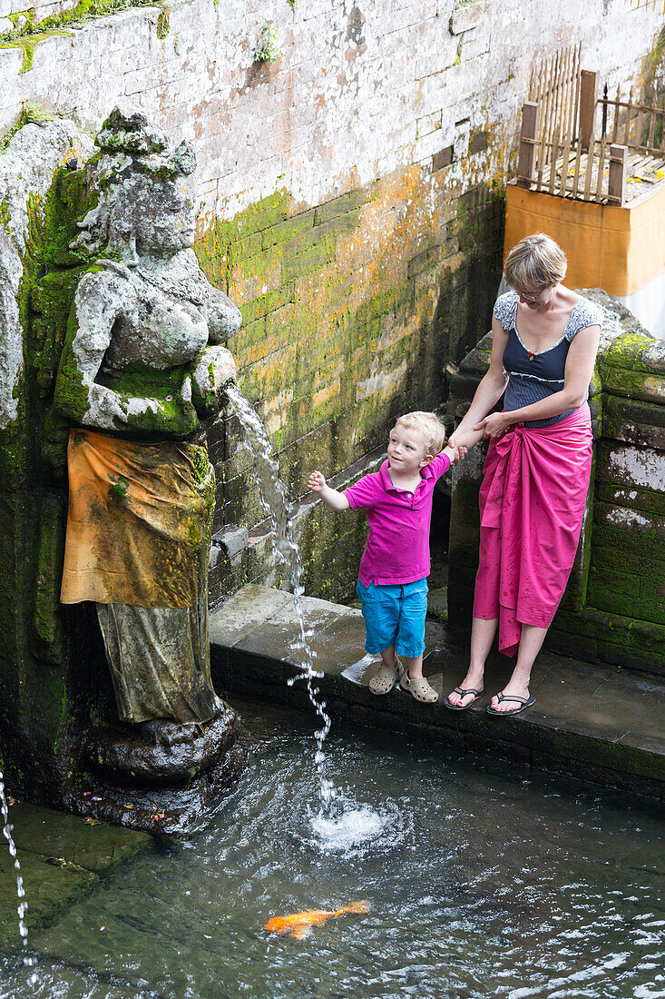 Mother and son playing with water, Balinese sculptures, parental leave, Ubud, Bali, Indonesia