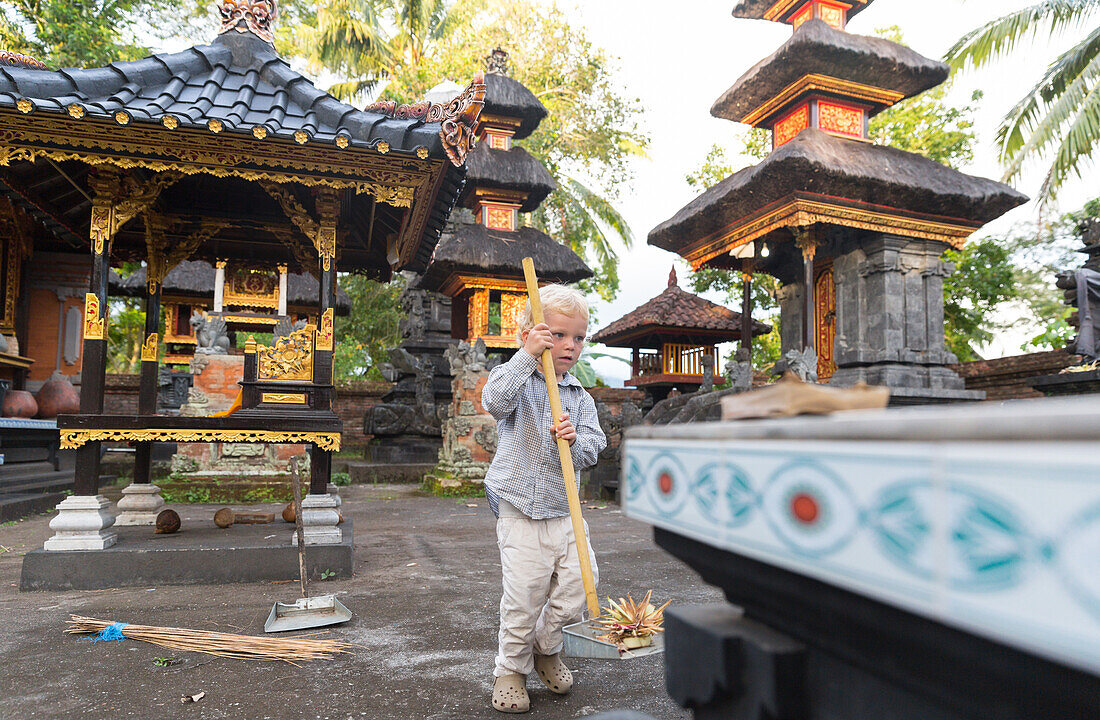 Kleiner Junge fegt im Tempel, Besen, putzen, kehren, aufräumen, typisch balinesischer Tempel, Junge 3 Jahre alt, blond, Elternzeit in Asien, Europäer, Deutsche, Westler, Familie, MR, Sidemen, Bali, Indonesien