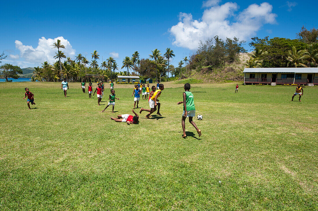 Village boys playing soccer on a field, palm trees in the distance, Sawa-i-Lau island, Yasawa Islands, Fiji, South Pacific