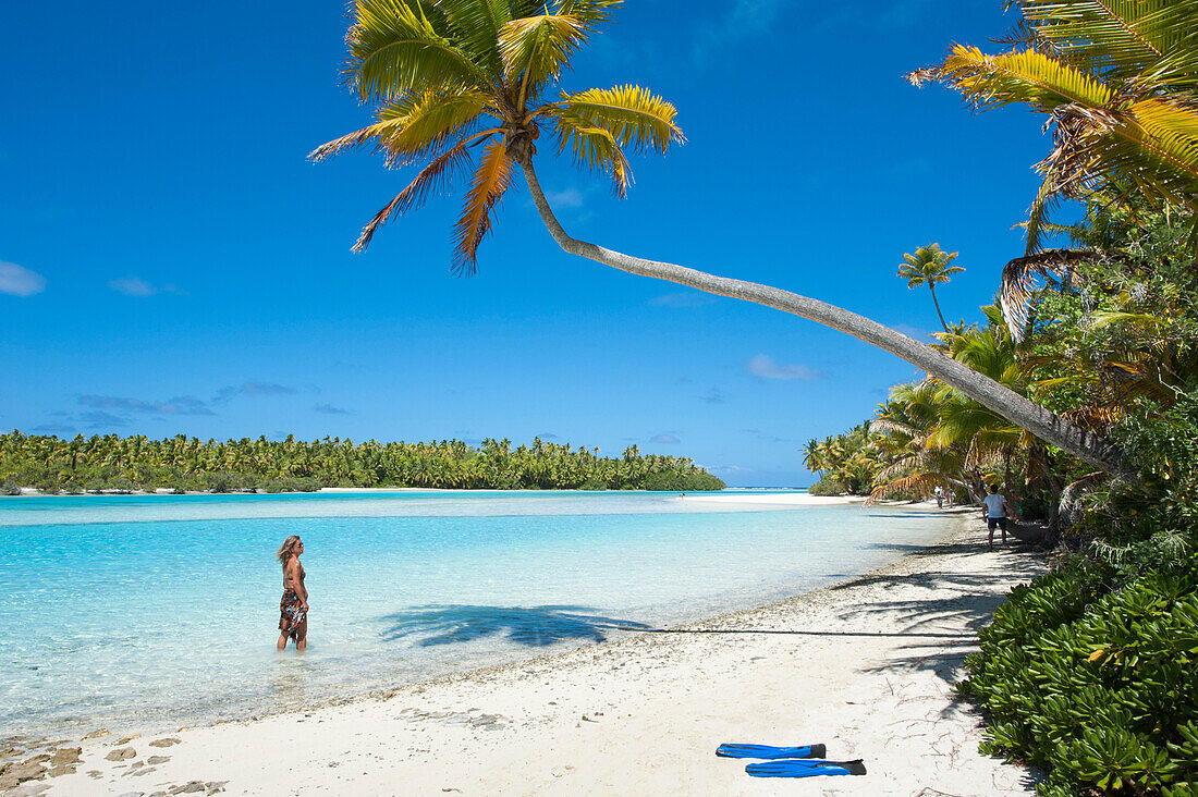 Woman strolling along the beach with palm trees at One Foot Island in Aitutaki Lagoon, Aitutaki, Cook Islands, South Pacific