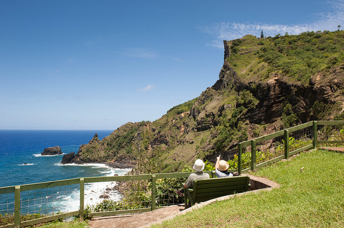 Paar sitzt auf Parkbank mit Blick zur Küste, Pitcairn, Pitcairninseln, Britisches Überseegebiet, Südpazifik