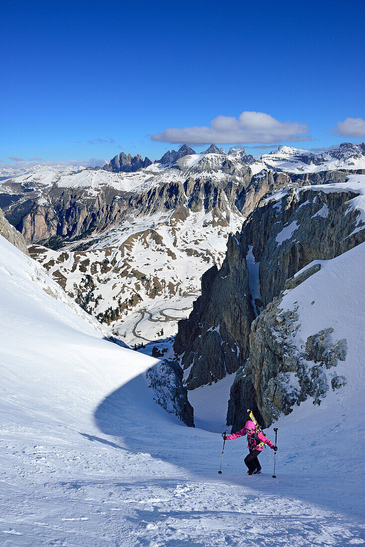 Frau auf Skitour steigt durch enges Couloir im Val Culea auf, Geisler im Hintergrund, Sella, Sellagruppe, Dolomiten, Südtirol, Italien