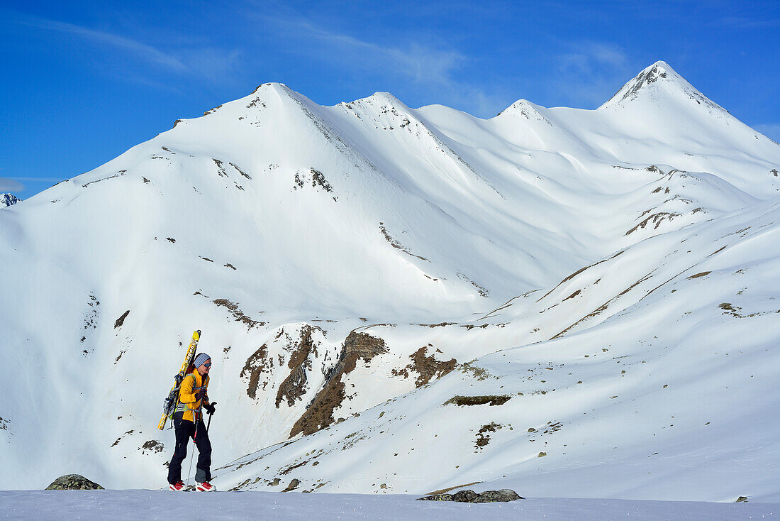 Female back-country skier ascending to Piz Kesch, Piz Blaisun in background, Engadin, Canton of Graubuenden, Switzerland
