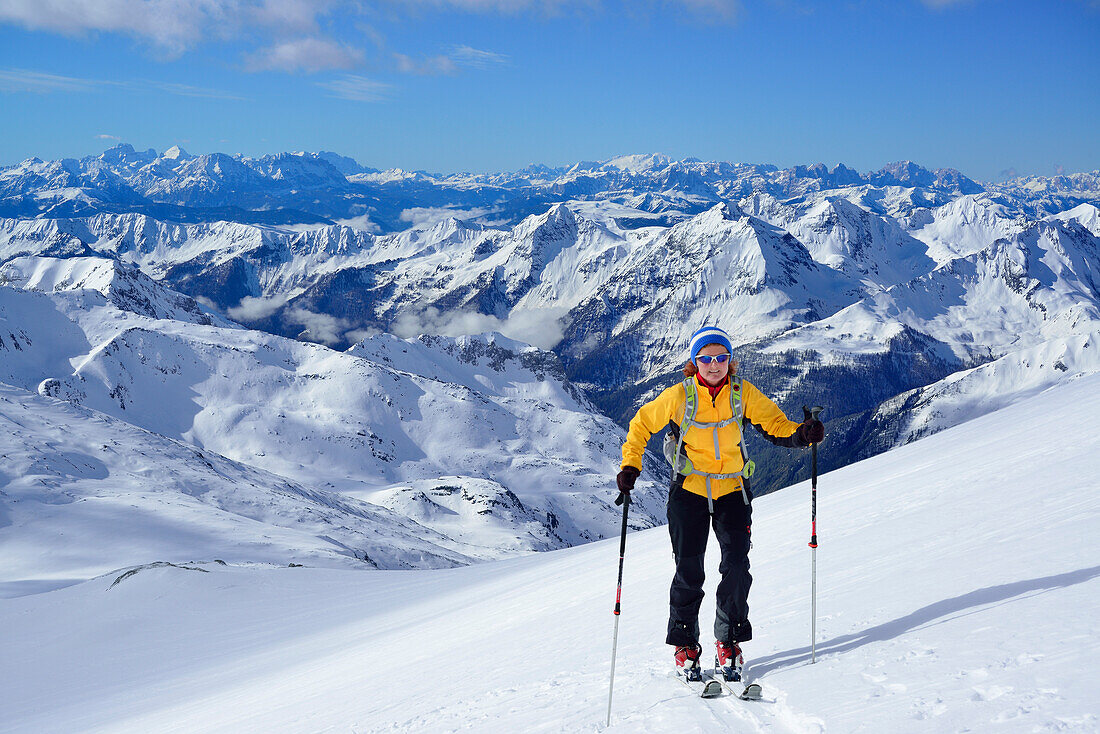 Female back-country skier ascending to Grosser Moeseler, Dolomites in background, Zillertal Alps, South Tyrol, Italy