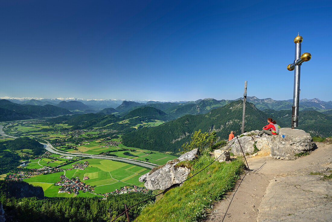 Hikers resting at summit cross on Kranzhorn with view over Inn valley, Chiemgau Alps, Tyrol, Austria