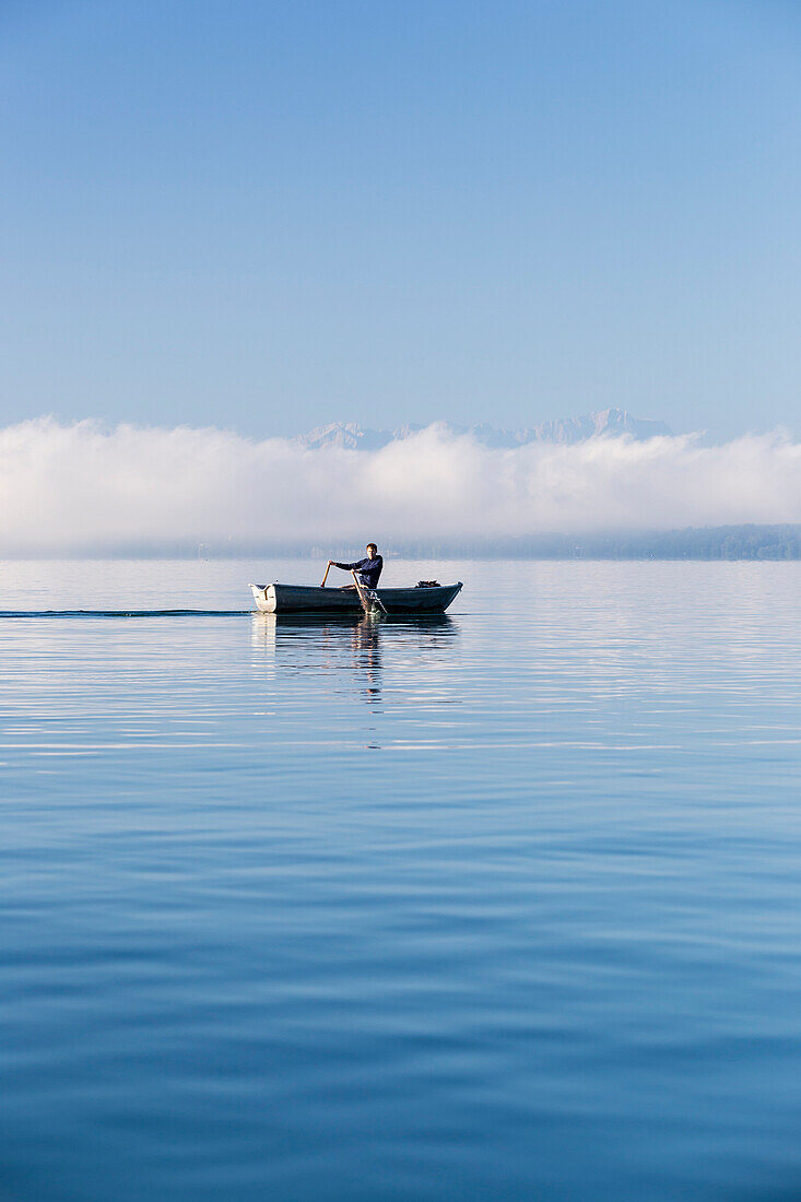 Mann in einem Ruderboot auf dem Starnberger See, Alpen mit Zugspitze im Morgennebel, Berg, Oberbayern, Bayern, Deutschland