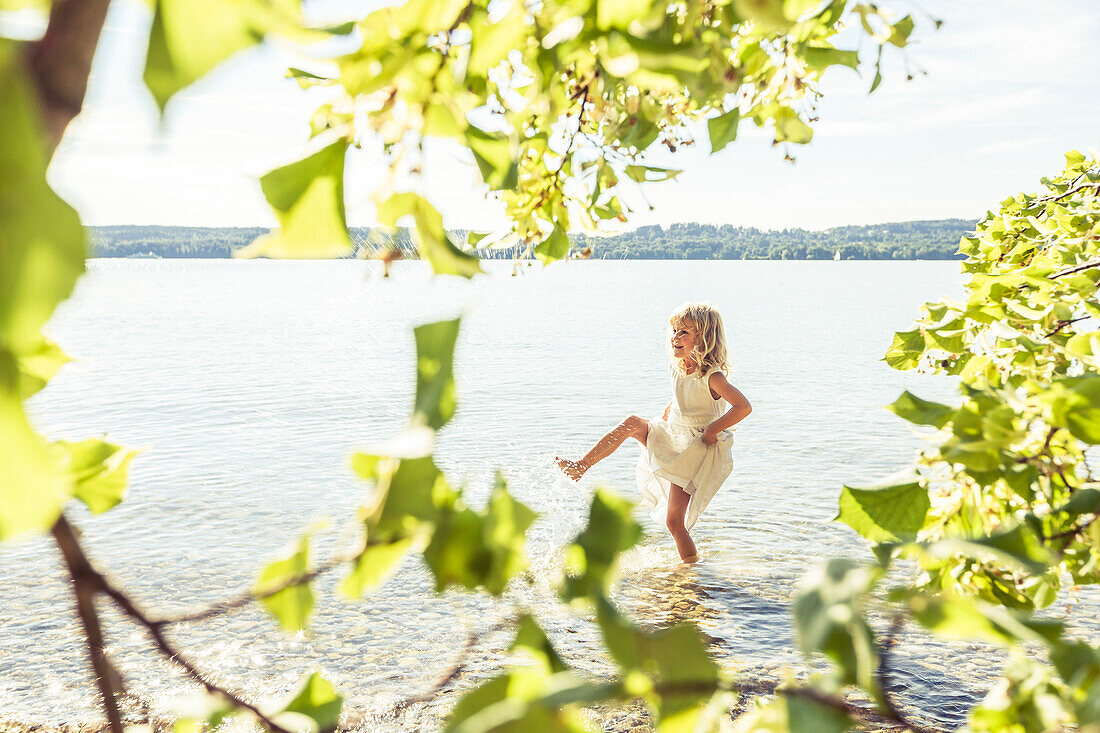 Girl wearing a summerdress standing in lake Starnberg, Berg, Upper Bavaria, Germany