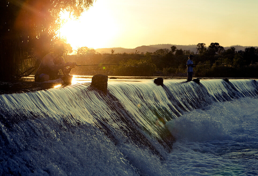 Angler auf dem Wehr der Parry Creek Road über den Ord River bei Sonnenuntergang, nahe Kununurra, Western Australia, Australien