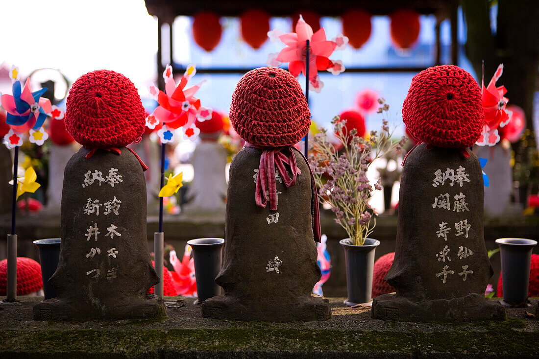 Drei kleine Steinfiguren mit gehäkelten roten Mützen, Shiba Park, Tokio, Region Kanto, Honshu, Japan