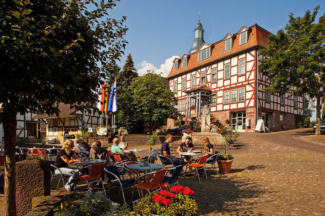 Menschen sitzen vor einem Café am Marktplatz mit Rathaus, Bad Zwesten, Nordhessen, Hessen, Deutschland, Europa