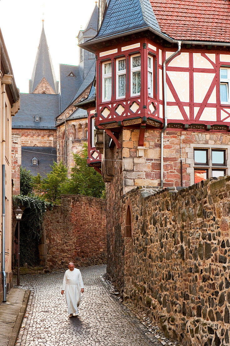 A Monk walking down the Titusgasse alley behind Fritzlar Cathedral, Fritzlar, Hesse, Germany, Europe
