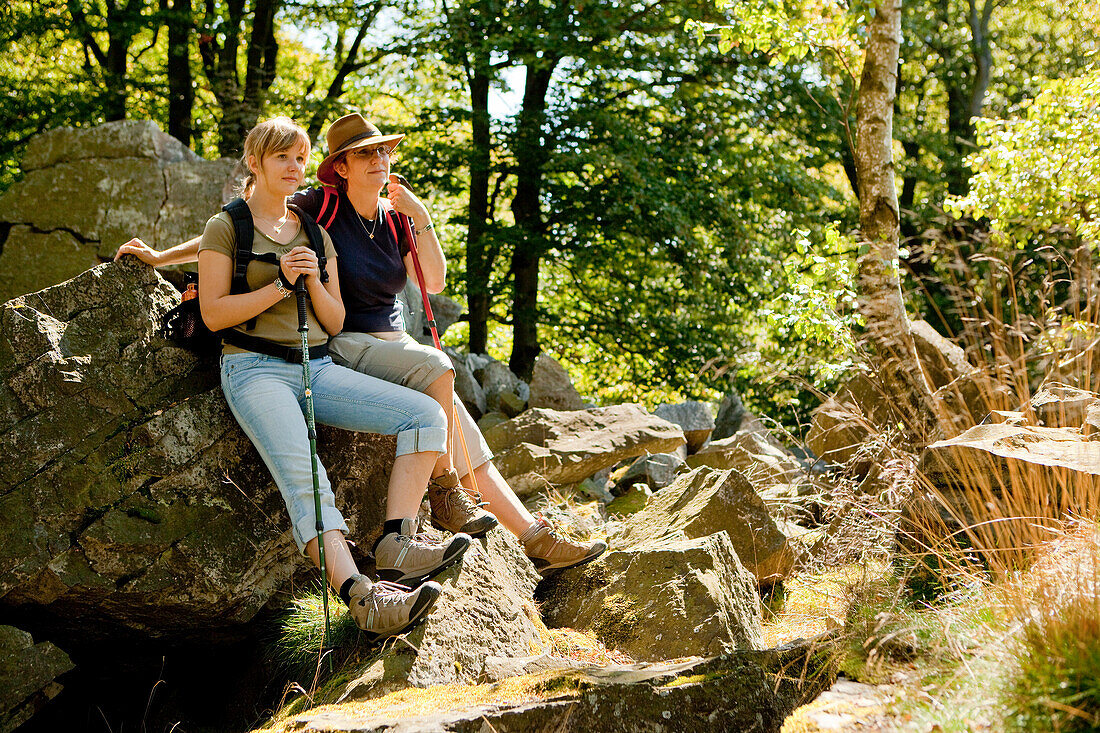 Two women resting along the Kellerwaldsteig hiking track at Wuestegarten in the Kellerwald forest in Kellerwald-Edersee National Park, Kellerwald, Hesse, Germany, Europe