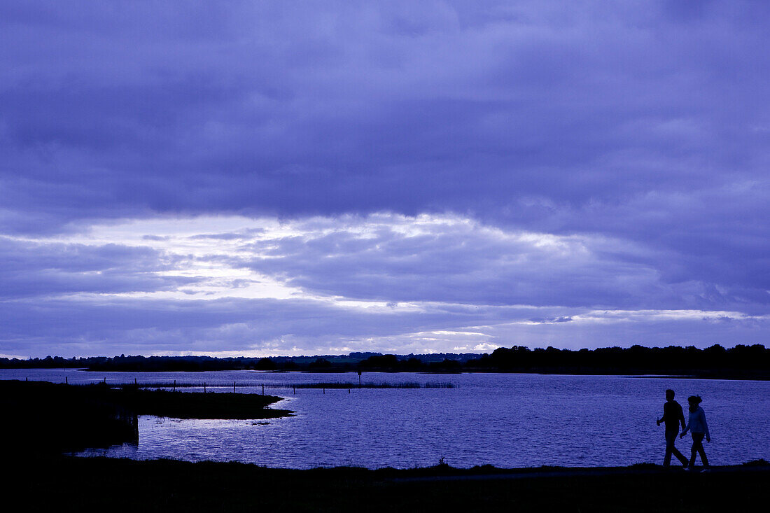 Paar läuft entlang Ufer vom Fluss Shannon im Dämmerlicht, Clonmacnoise, County Offaly, Irland, Europa