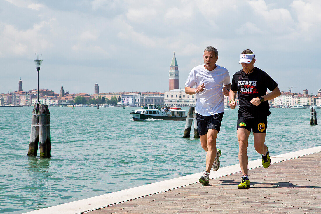 Zwei Männer joggen am Ufer des Biennale-Gürtels, Venedig, Venetien, Italien, Europa