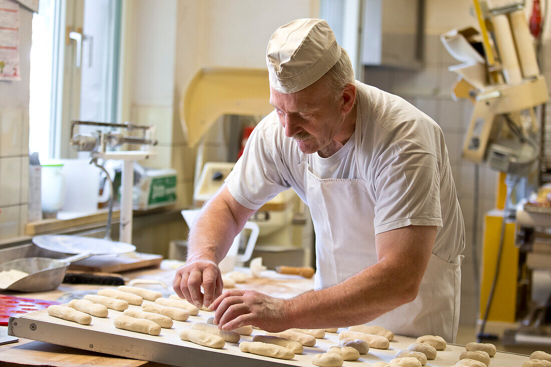 Baker Erwin Oehl making breadrolls in his bakery, Frankenau, Hesse, Germany, Europe