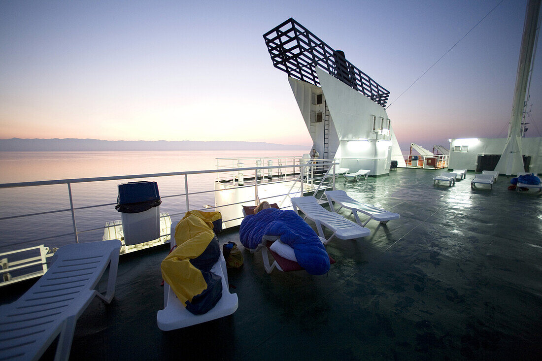 On the deck of a trans-Adriatic car ferry crossing an adventurous travelers sleep.