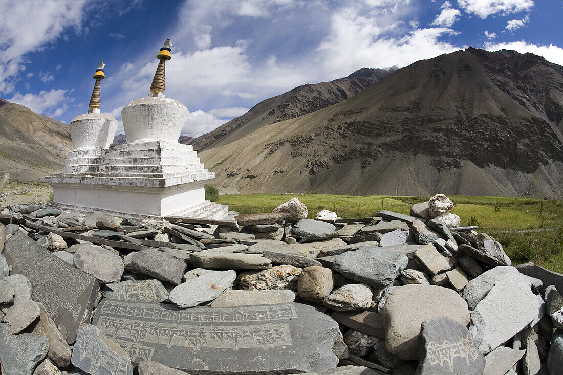 Buddhist chortens or stupas and mani stones lie in green valley, Zanskar Mountains, Ladakh, northern India.  This predominantly Buddhist area  is near the border with Tibet, China.