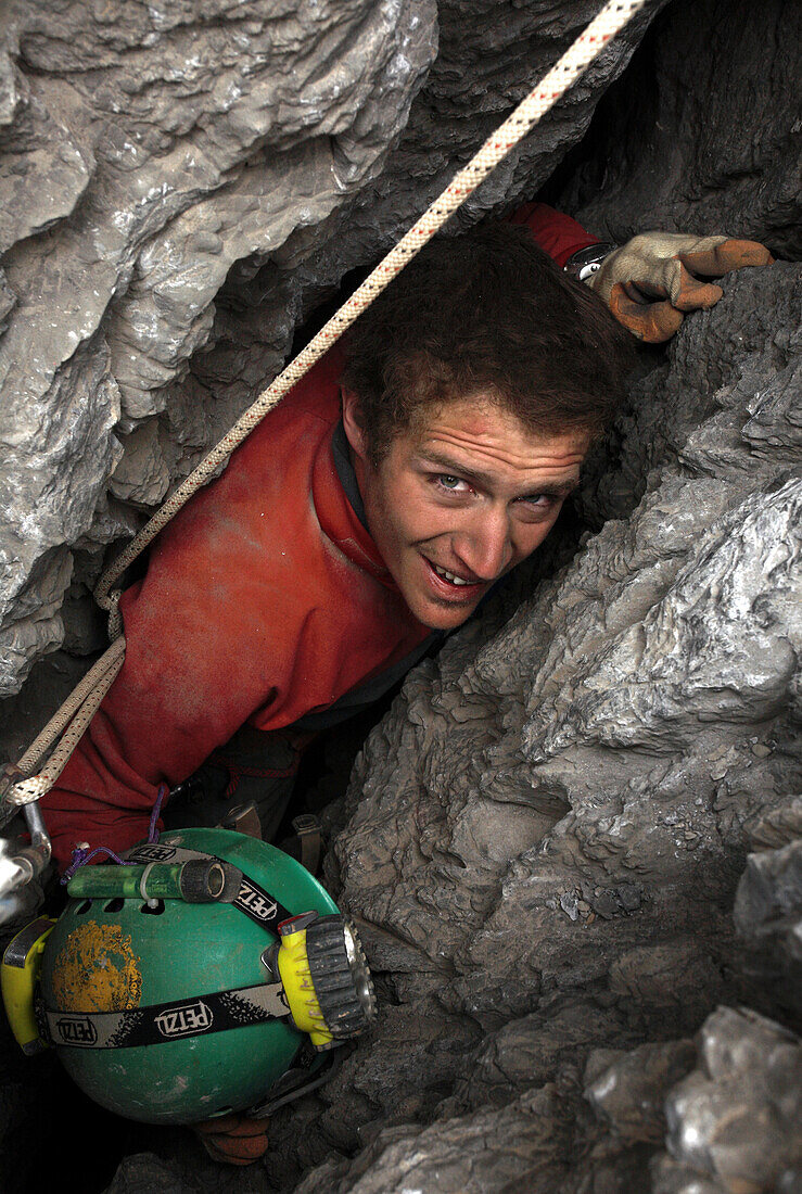 Rob Eavis has to remove his helmet in order to pass the tight squeeze in an entrance to a cave in the White Mountains on the island of Crete.