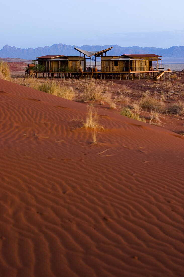 Early morning light glows on the Wolwedans Mountain View Suite in the Namib Rand Nature Reserve in Namibia. The suit is surrounded by the ever changing burnt orange wind swept dunes.