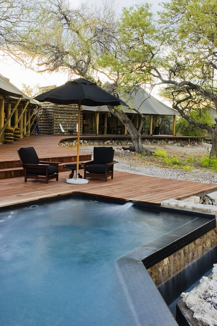An infinity pool and lounge chairs under the canopy of shade at Onguma tented camp on the Onguma Private Nature Reserve, Etosha National Park - Namutoni Gate.