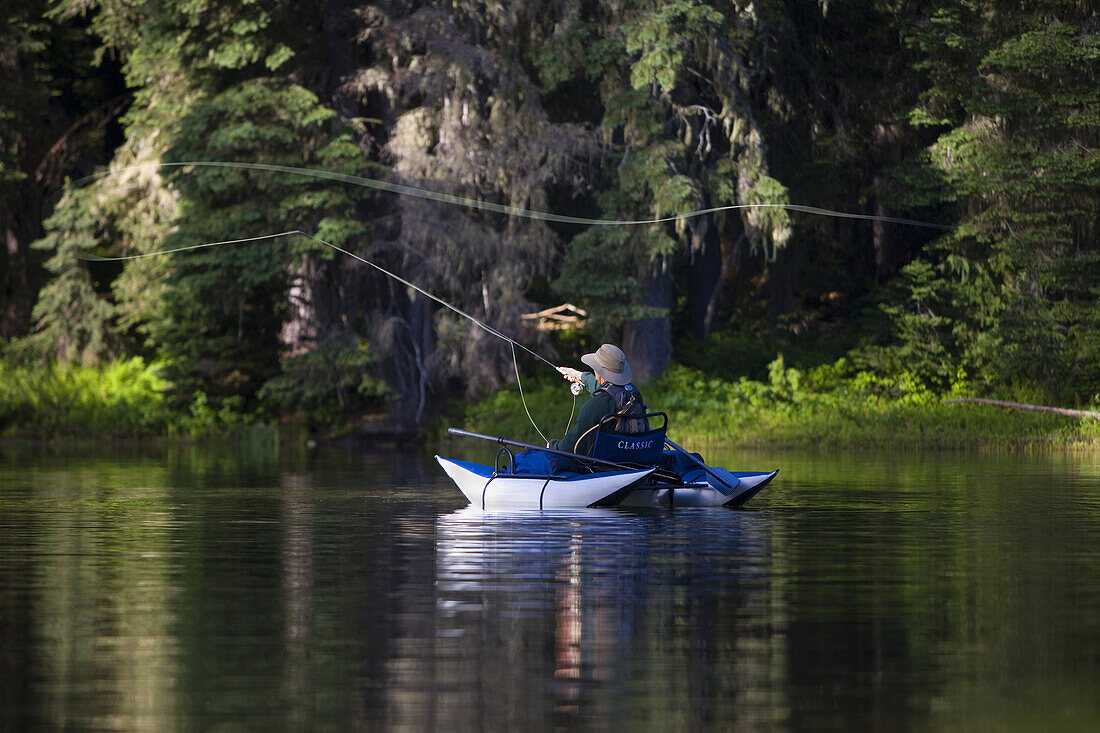 Matt Pontius, casts a fly from his pontoon boat on a small lake in the Cascade Mts. of Washington State.