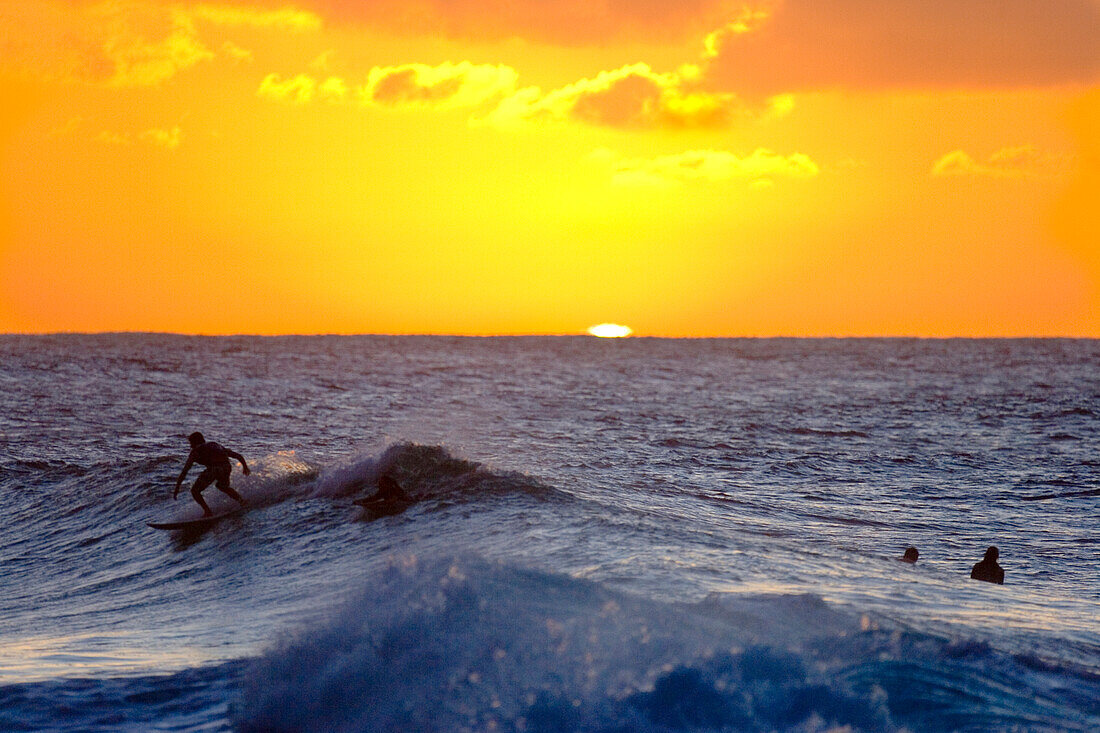 the green flash from the setting sun on the north shore of Oahu, Hawaii, with  surfer unidentifiable