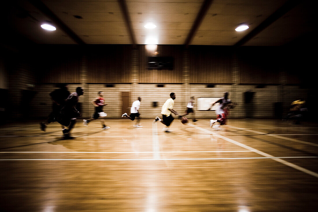 A game of basketball as players run down the court.