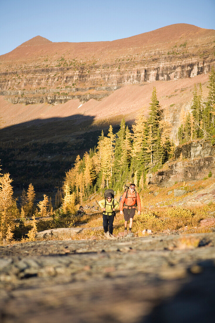 Two men backapcking in late evening light high in Rocky Mountains of Glacier National Park, MT in remote area near Hole-in-the-wall - Greg Franson & Pete Thomas.