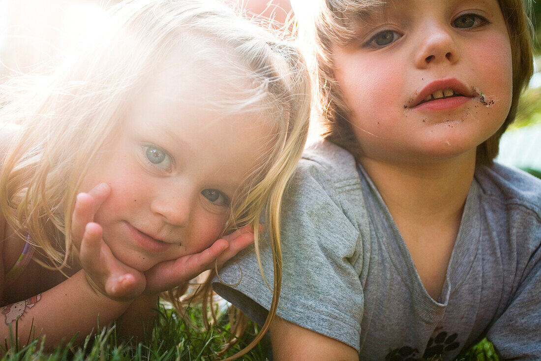 Two small kids smile for the camera in the garden. releasecode: sloan_cordon, kieran_reilly
