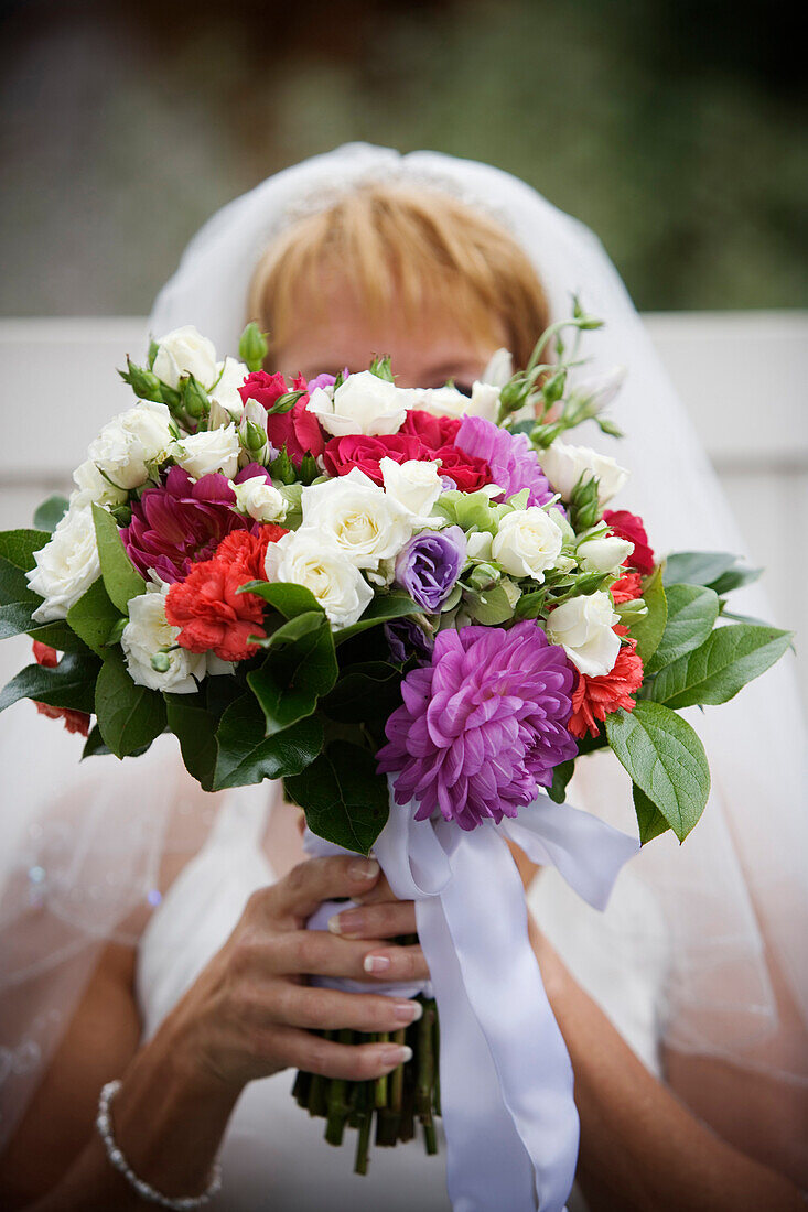 'A bride holding her wedding bouquet in front of her face. releasecode; rrk_mr142,'