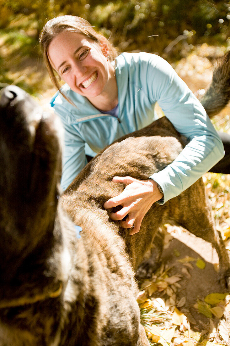 Tina Sommer scratching, loving and playing with  her dog Roxy while taking a break from trail running the trails near Santa Fe, New Mexico in the cool fall season.