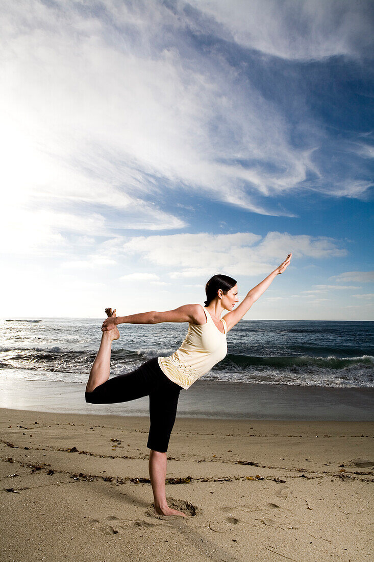 A women at the beach performing yoga and meditation.