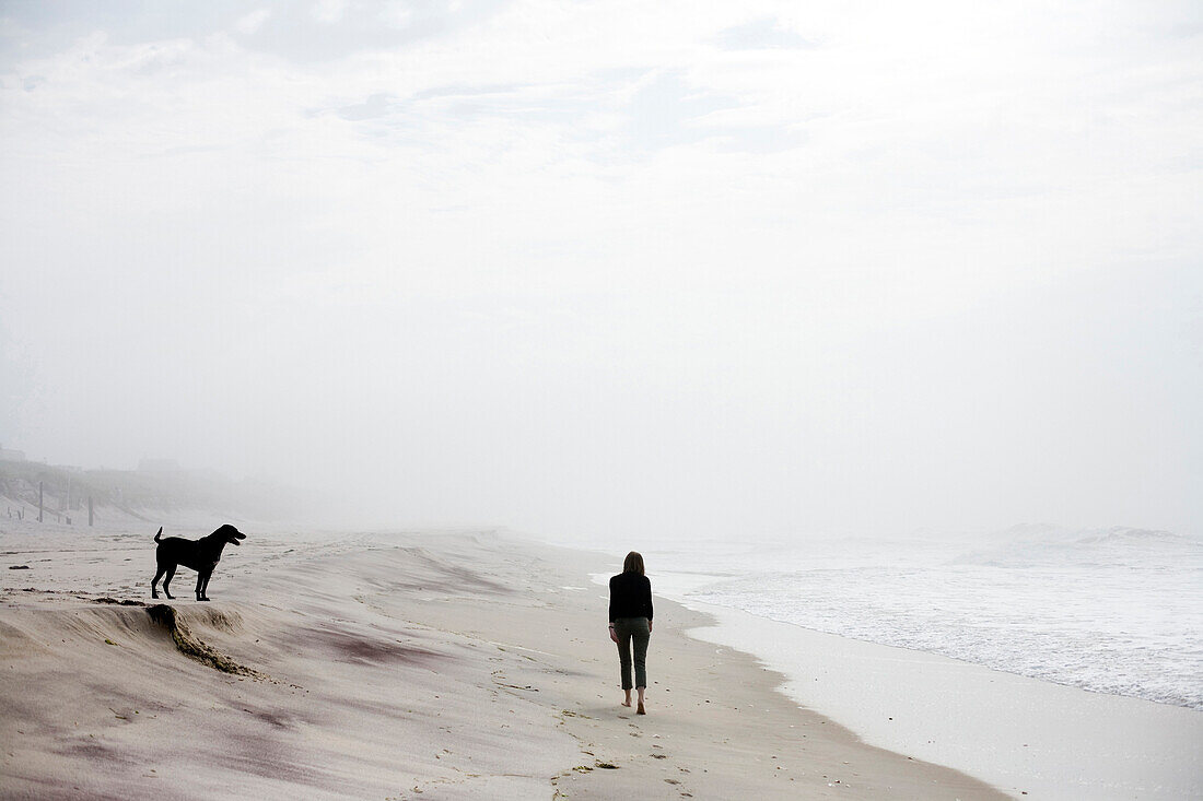 Catherine Lucey, 28, takes a morning walk on a foggy beach with her dog in the Hamptons in New York state on July 6, 2007. releasecode: rd_pr0004