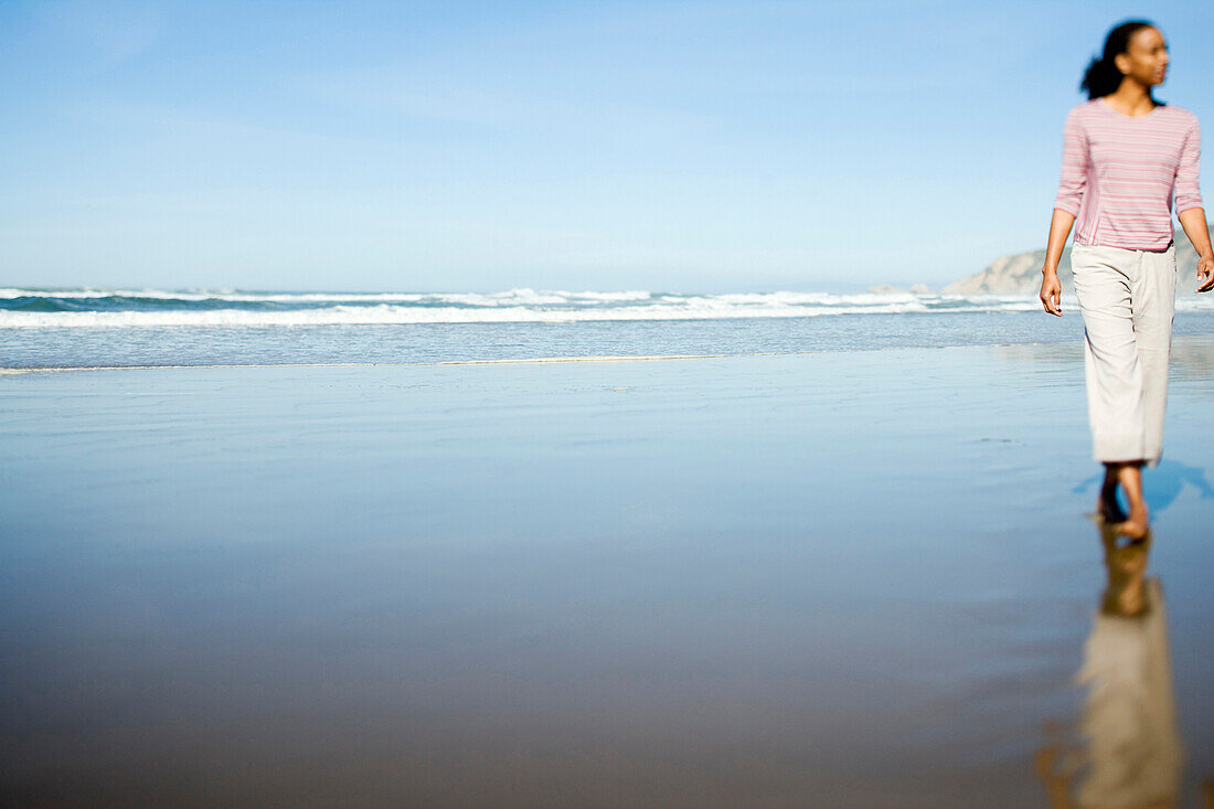 An African-American woman enjoys a morning walk on a beautiful California beach.