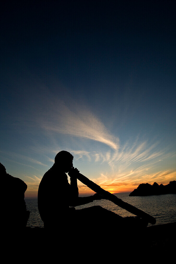 A man plays didjeridu, an old Australian instrument, at sunset on a beach near Heraklion, Crete, Greece. releasecode:floros001