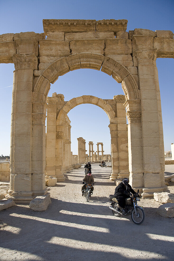 Palmyra, Syria - January, 2008: Motor bikers take a shortcut through Roman ruins in the desert.  Palmyra or Tadmore was a 2nd century AD desert oasis used as a strategic staging post for caravans traveling between the Mediterranean Sea and the east.  It w