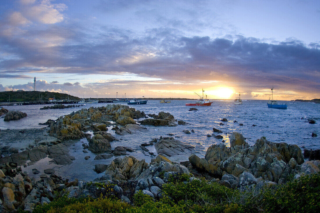 Wide angle view of the sun setting over Currie Harbour on King Island, Australia.